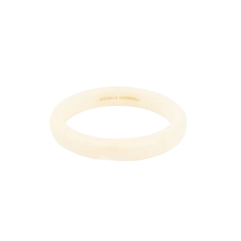 Cream-colored Betty Bangle with a smooth, rounded finish and gold brand engraving on the inside.