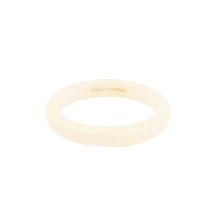 Cream-colored Betty Bangle with a smooth, rounded finish and gold brand engraving on the inside.