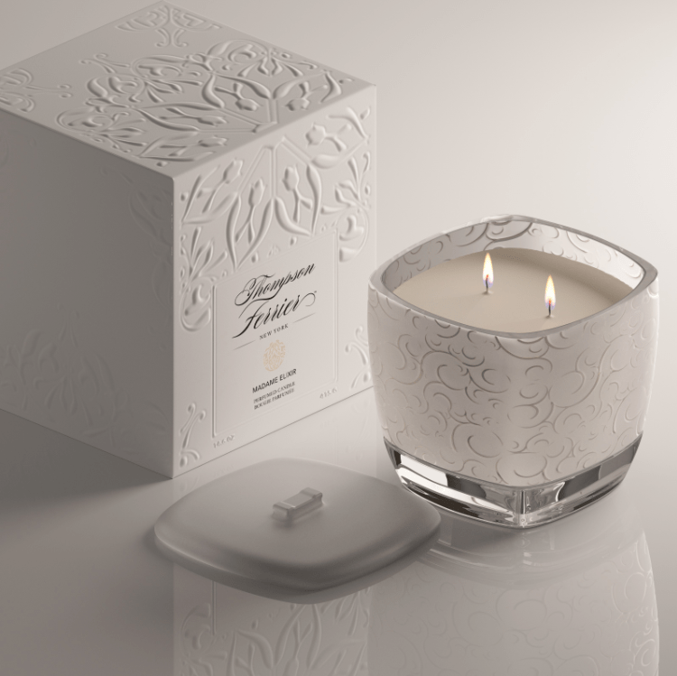 Madame Elixir Candle in a cylindrical glass jar with a black lid.
