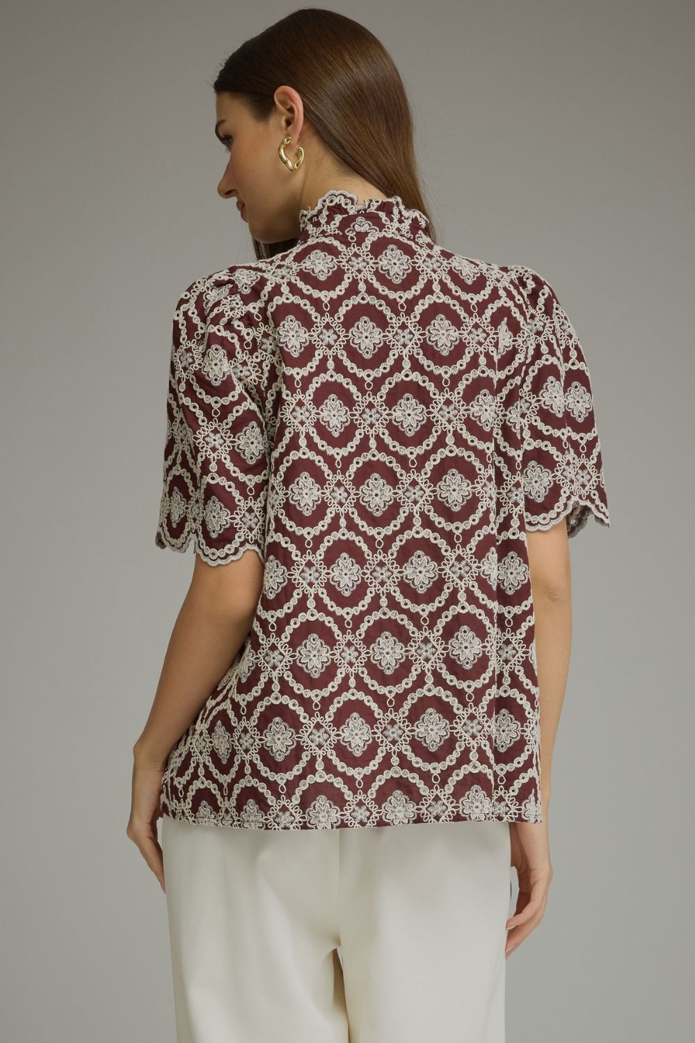 Back view of a woman wearing a burgundy Amalia top with white geometric embroidery and puff sleeves.