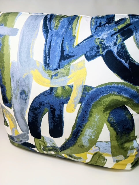 A 24x24 hand-crafted pillow with a blue, green, and yellow abstract brushstroke pattern on a white background.