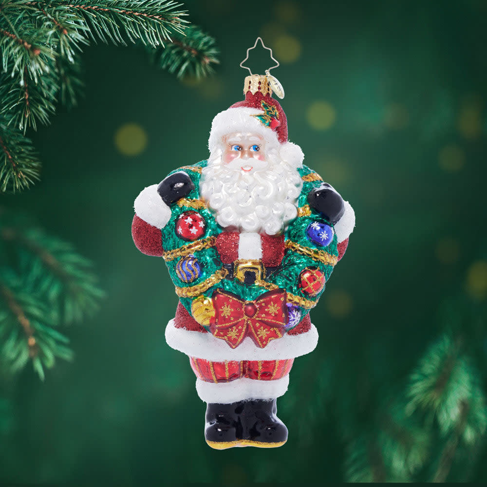 Santa Claus figurine holding a green wreath with red berries.