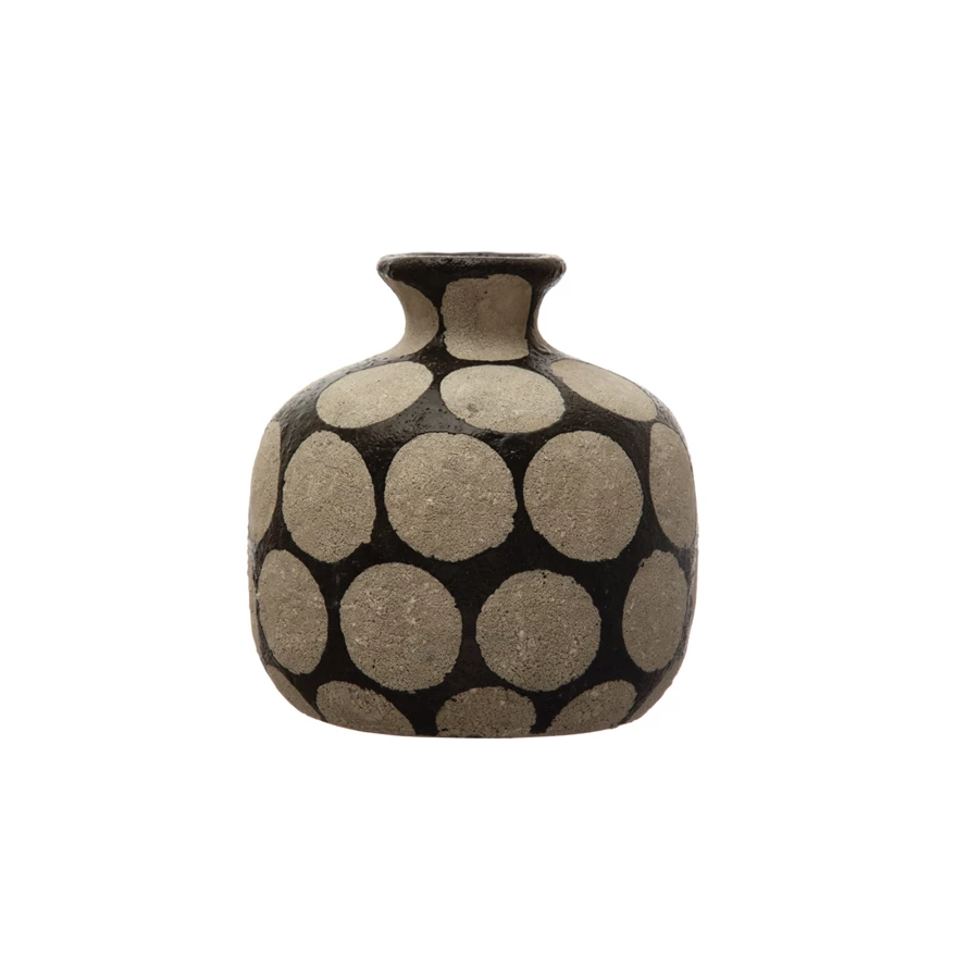 Terracotta vase with black wax relief dots on a cement finish.