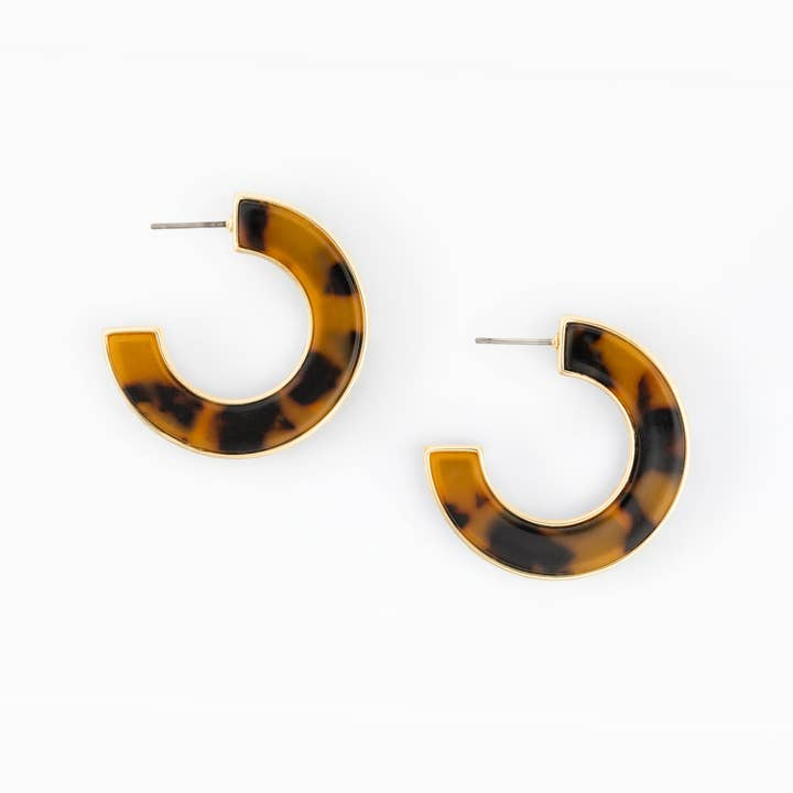 Junie Earrings featuring a gold-trimmed tortoiseshell resin hoop design on a white background.