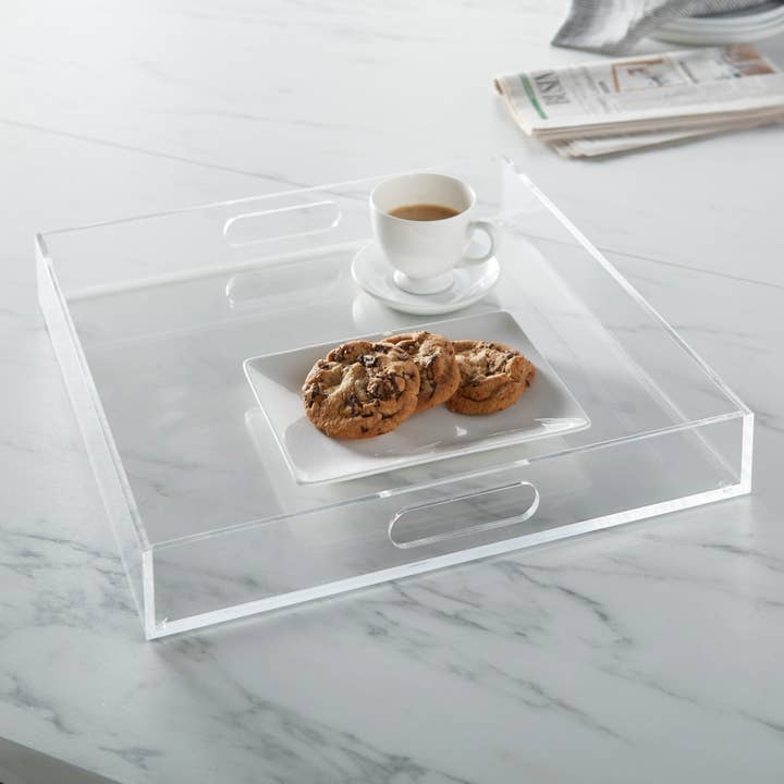 16 inch square clear acrylic serving tray with handles on a marble surface with coffee and cookies.