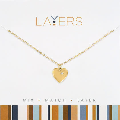 Gold heart pendant necklace with a small inset crystal on a gold chain, displayed on a card.