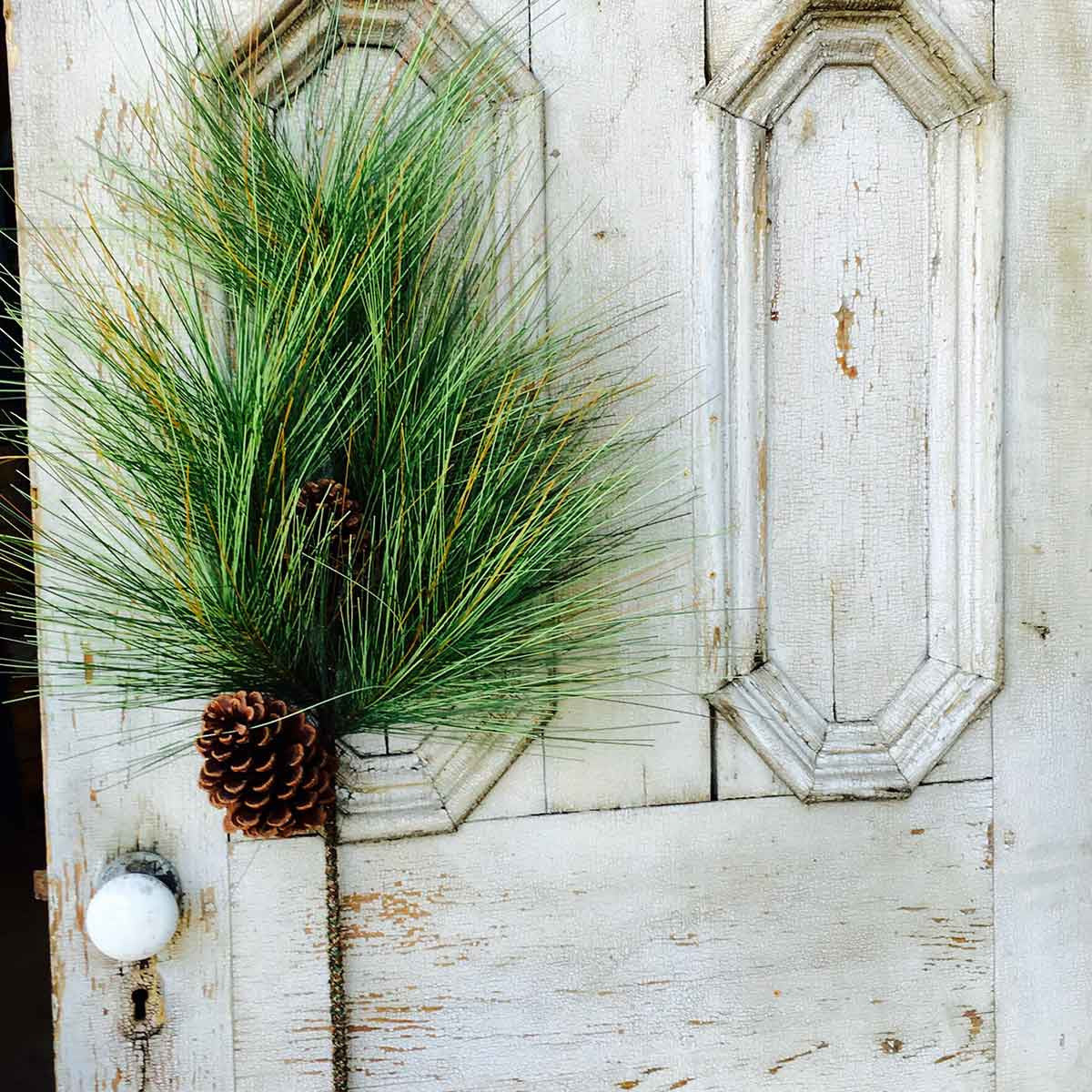 35-inch giant pine and sugar cone spray with long green needles against a rustic white door.