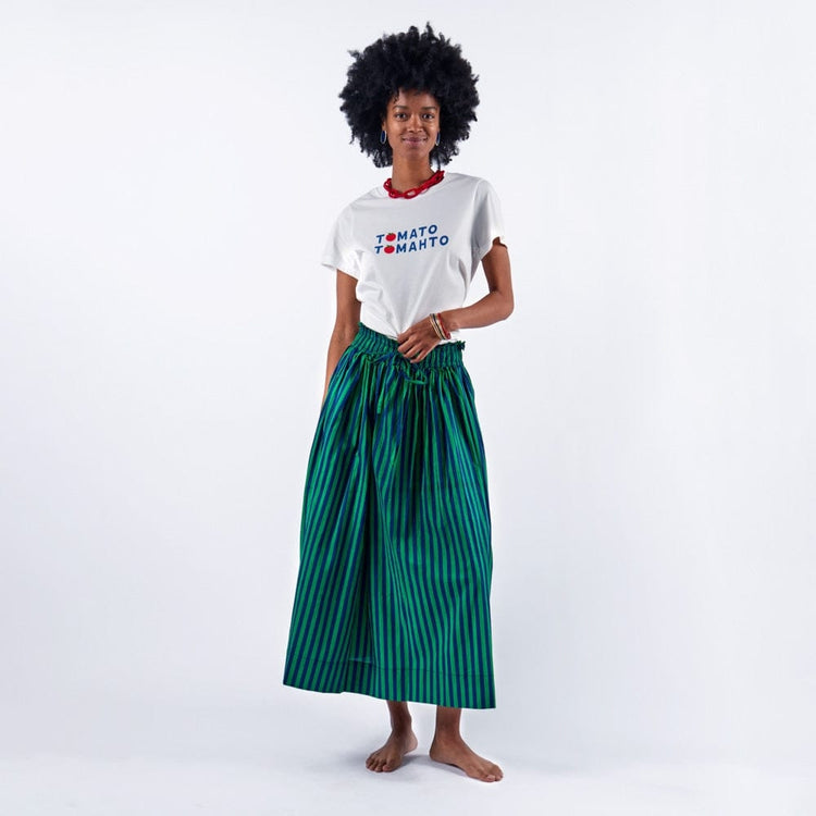 Woman wearing the Kiki Tee Tomato Tomahto white graphic t-shirt with a green striped maxi skirt.