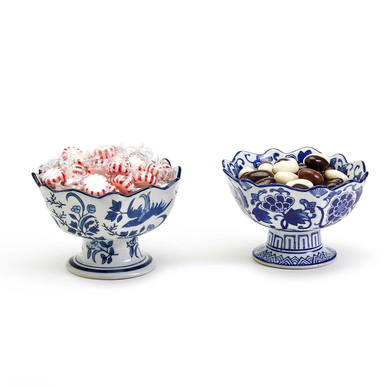 Two hand-painted blue and white porcelain footed bowls with scalloped edges holding candy.