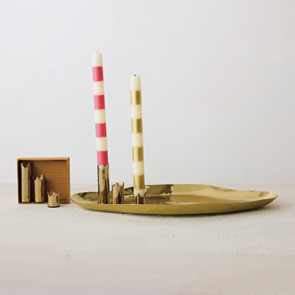 Set of 6 gold metal magnetic crown-shaped taper holders on a matching tray with striped candles.
