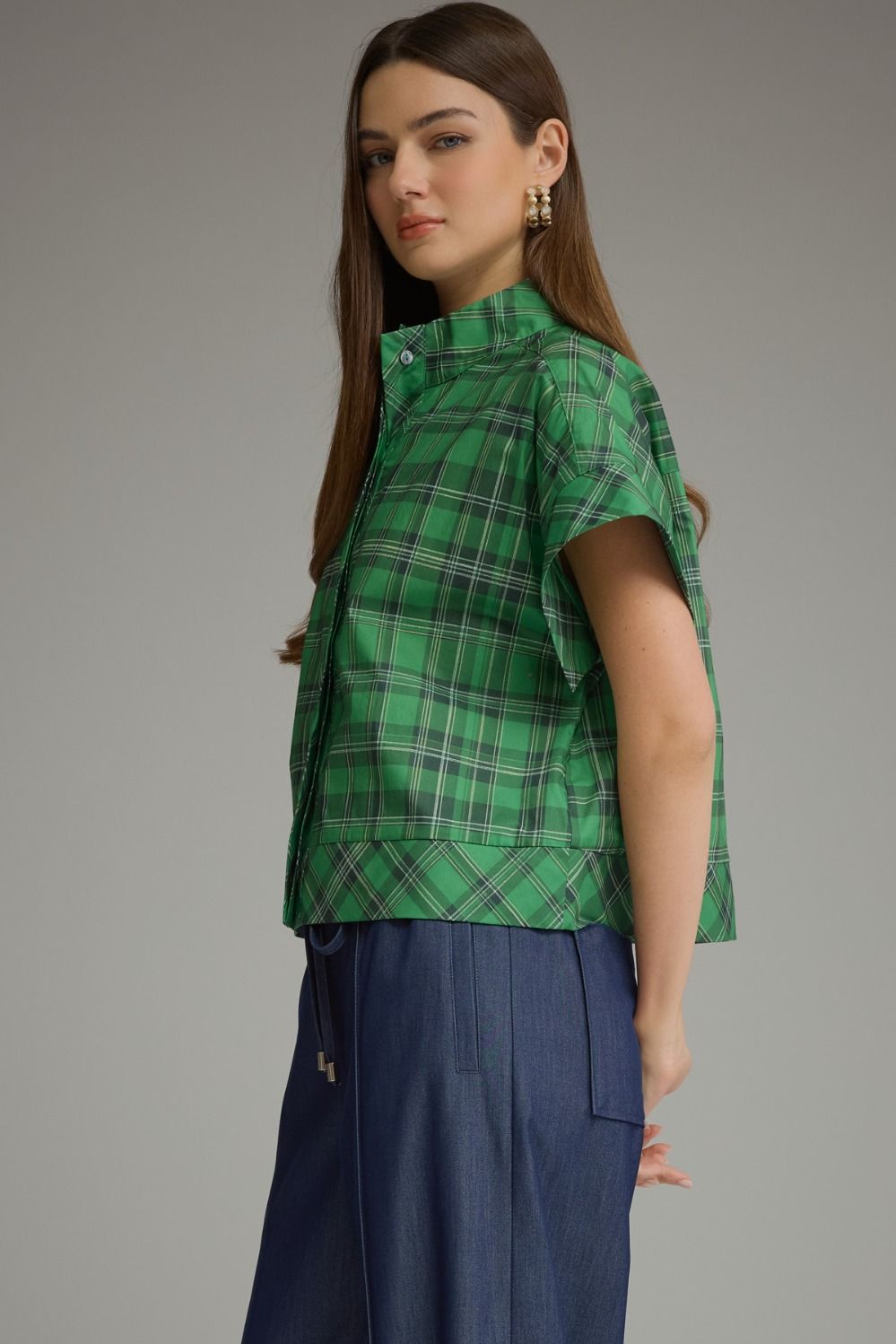 A woman wearing the Chloe green plaid short sleeve top with navy blue trousers.
