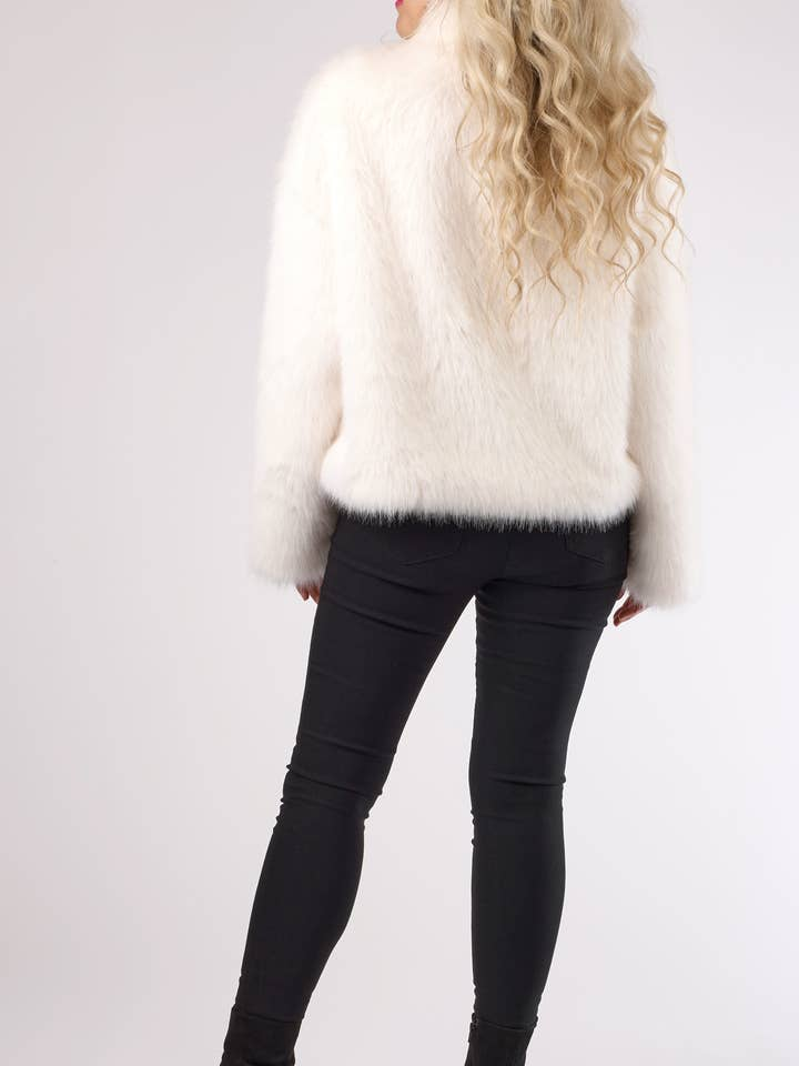 Back view of a woman wearing a white plush faux fur jacket with black skinny jeans.