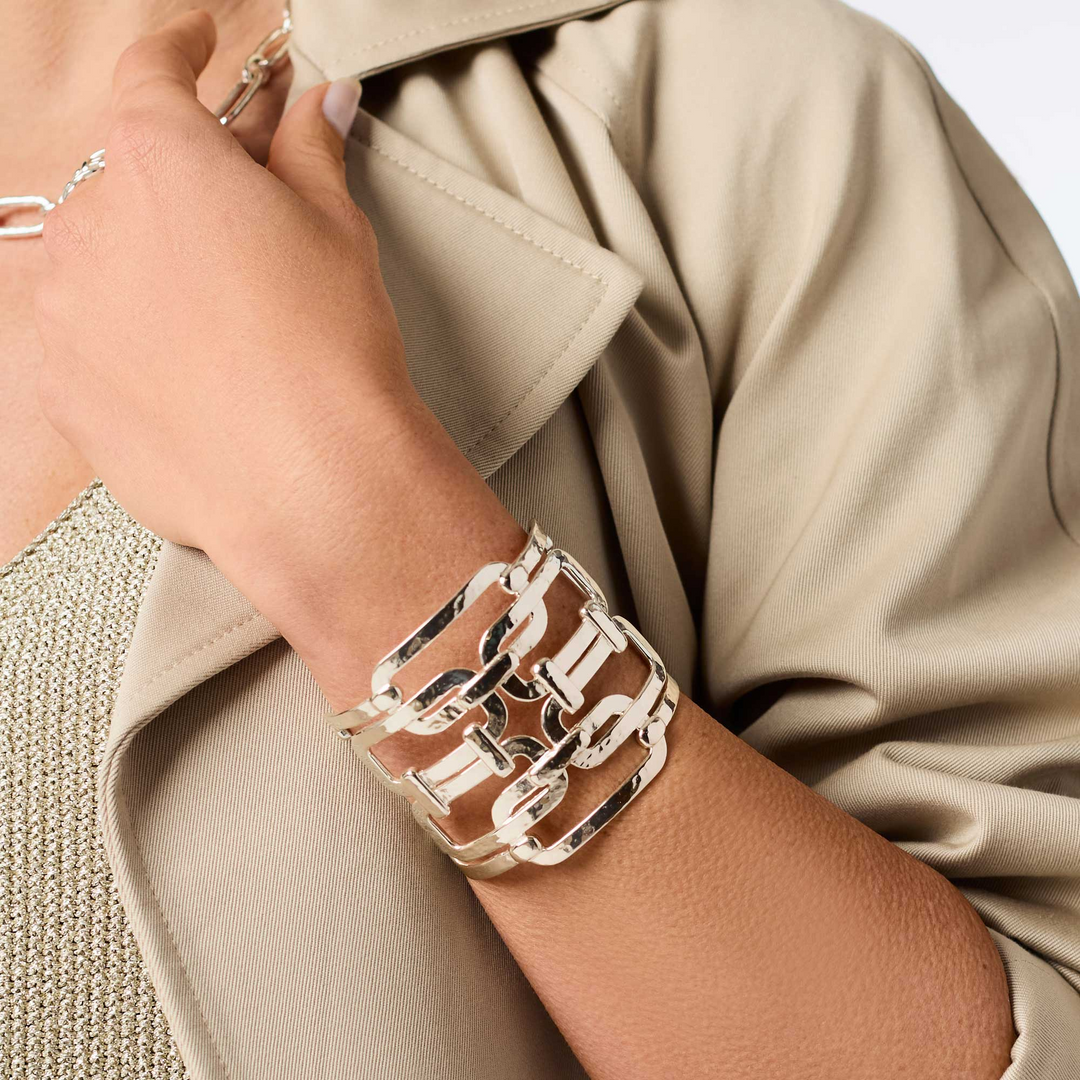 A person wearing the Sahara Statement Cuff Silver, a wide, open-work silver-toned metal bracelet.