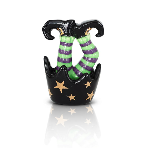 Ceramic witch legs with green and purple striped socks in a black star-spangled cauldron.