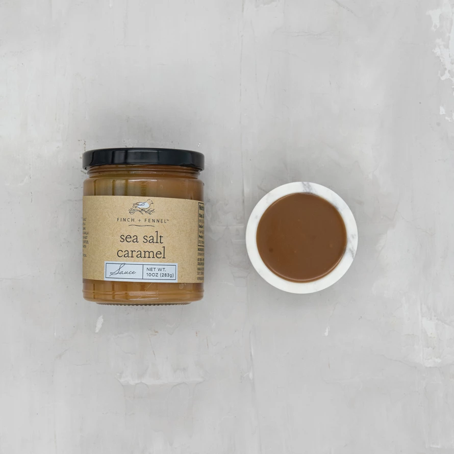 Glass jar containing sea salt caramel sauce with a visible swirl texture.