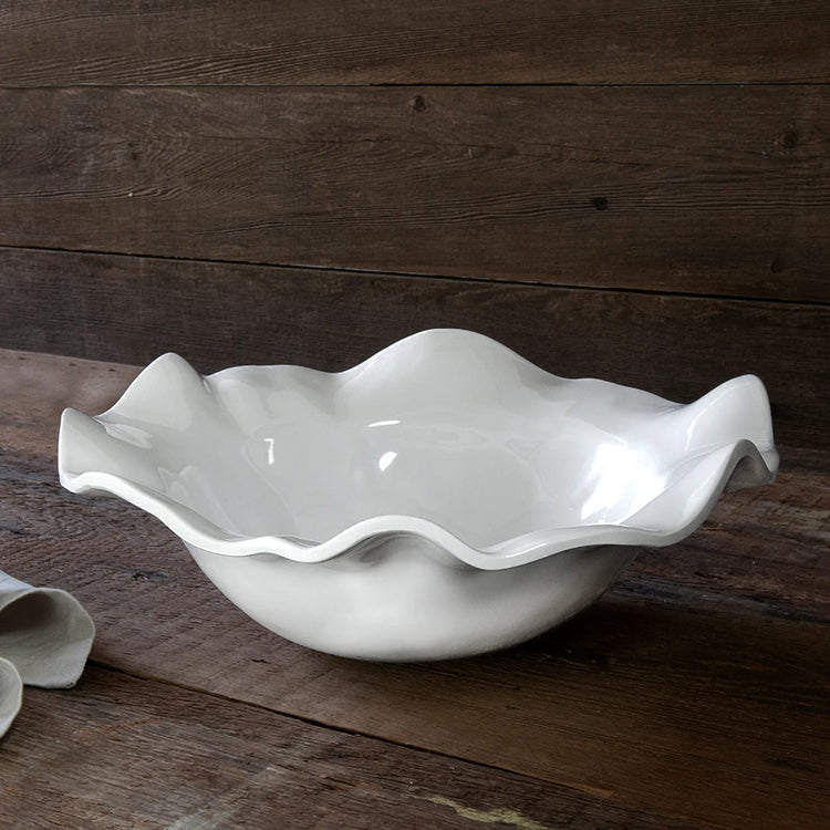 VIDA Havana white medium bowl with a wavy, ruffled rim on a rustic wooden surface.