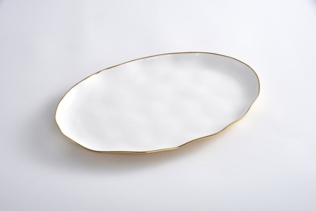 White oval porcelain tray with an irregular wavy edge and a gold titanium rim.