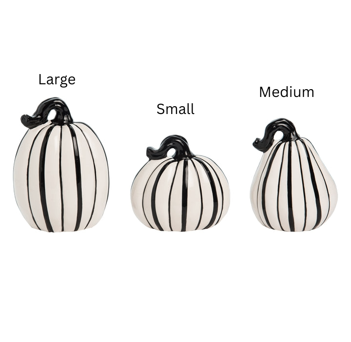 Three slim white ceramic pumpkins with black vertical stripes in large, medium, and small sizes.