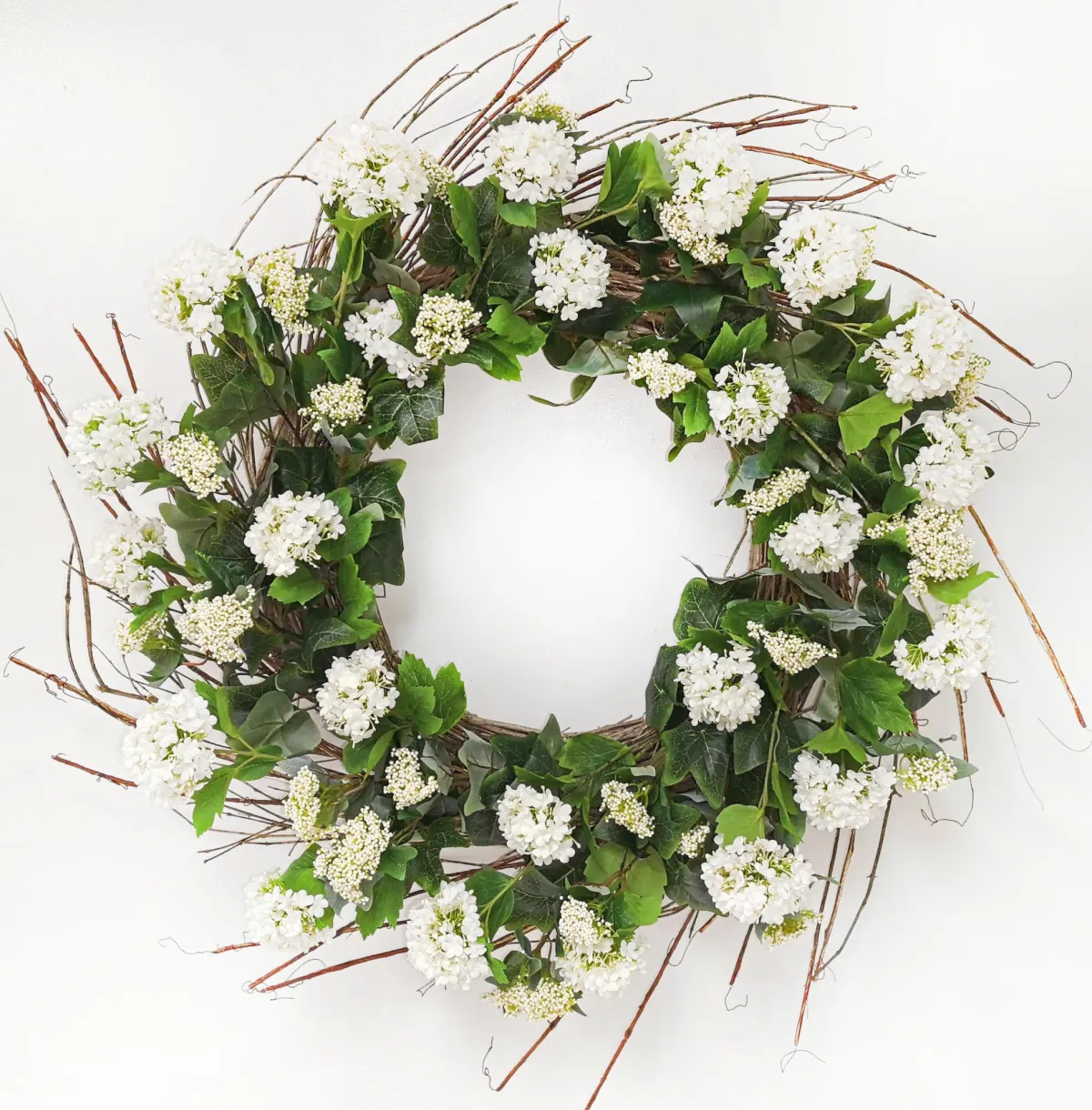 White snowball wreath with natural foliage arranged in a circular shape.