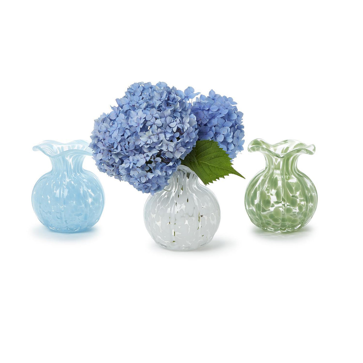 Three ruffled edge spotted glass vases in blue, white, and green, one holding blue hydrangeas.
