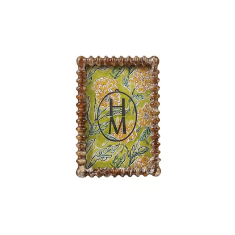 Marbled resin frame with scalloped edges and a yellow floral pattern on a green background.