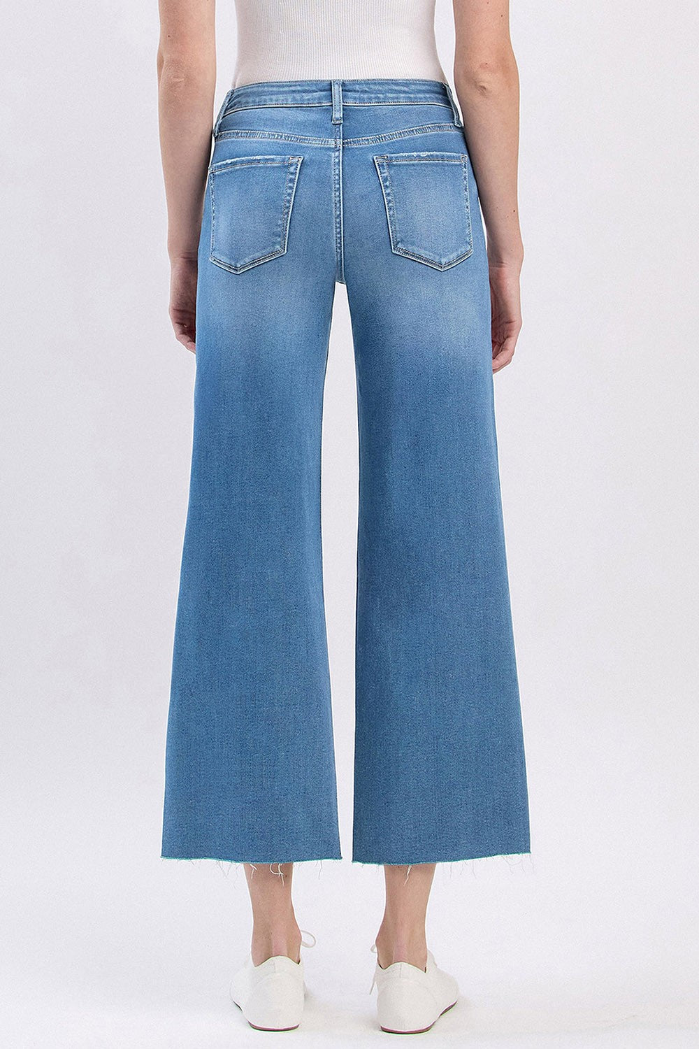 Back view of Audrey high rise slim wide leg cropped jeans in light wash with raw hems.