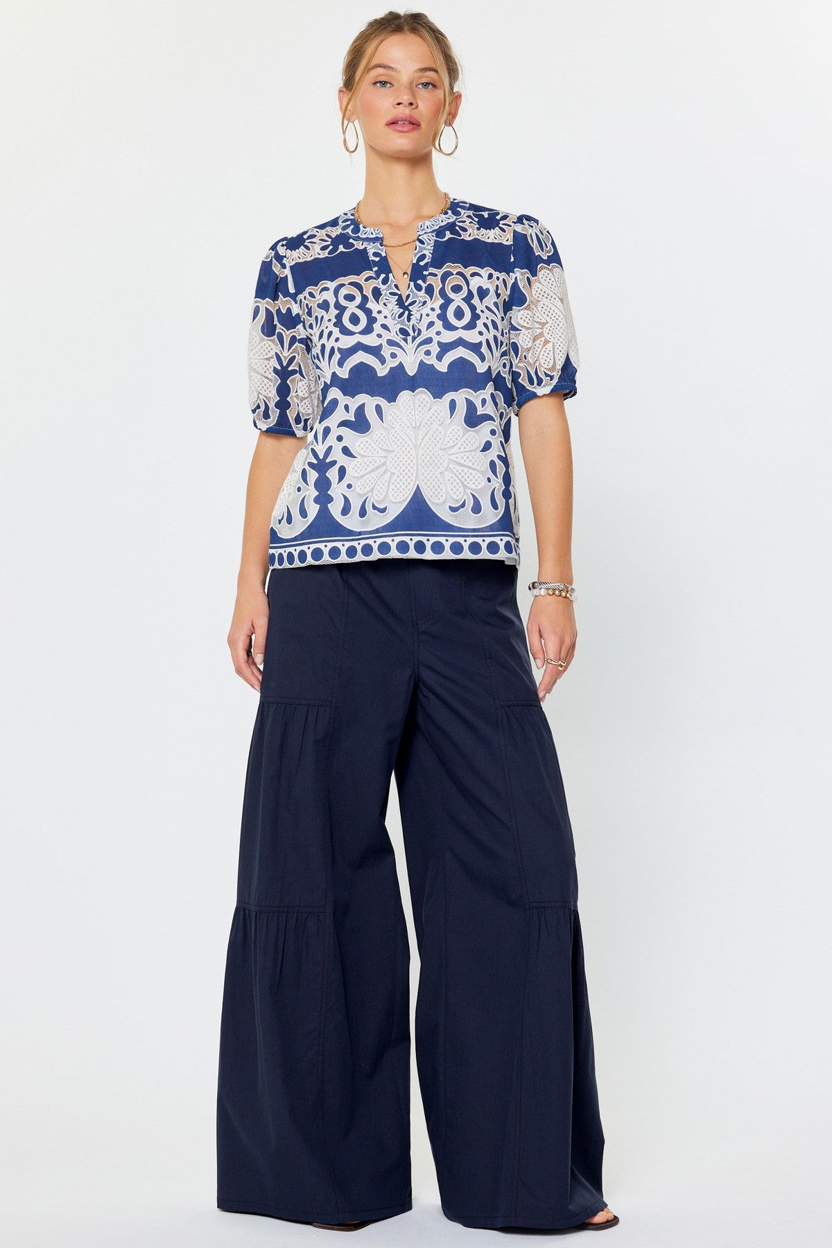 Relaxed fit rayon blouse with all-over lace embroidery floral medallions, split v-neckline, short puff sleeves, and inner cami lining.
