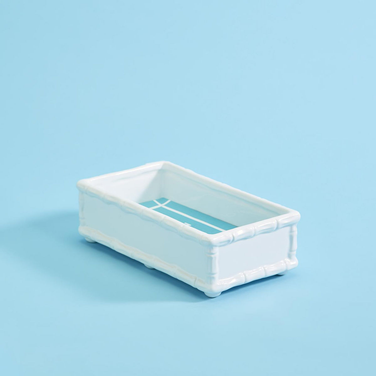 White ceramic faux bamboo guest towel holder with a blue and white fretwork pattern inside.