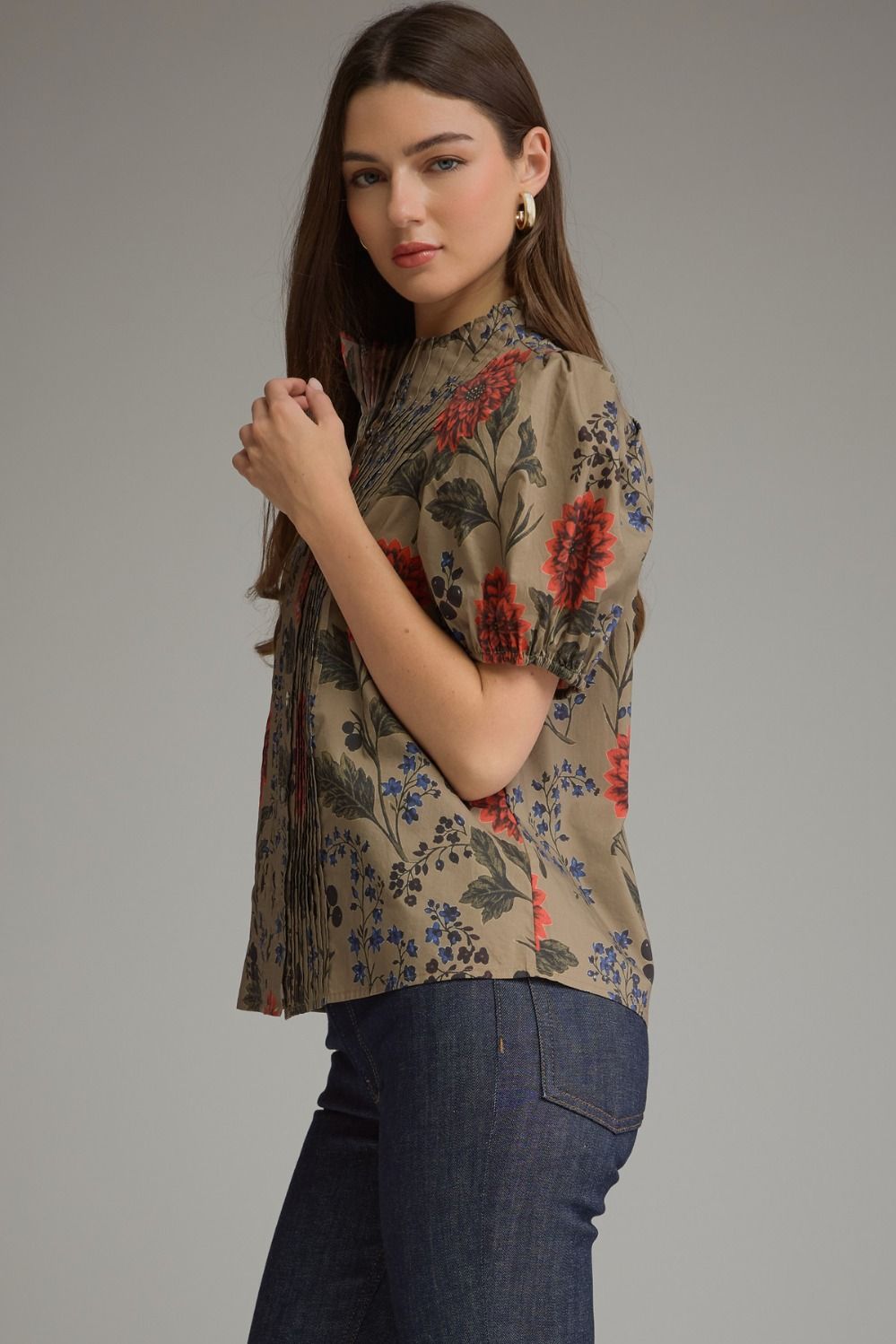 Woman wearing a khaki Amanda Floral Short Puff Sleeve Top with pintuck details and dark blue jeans.