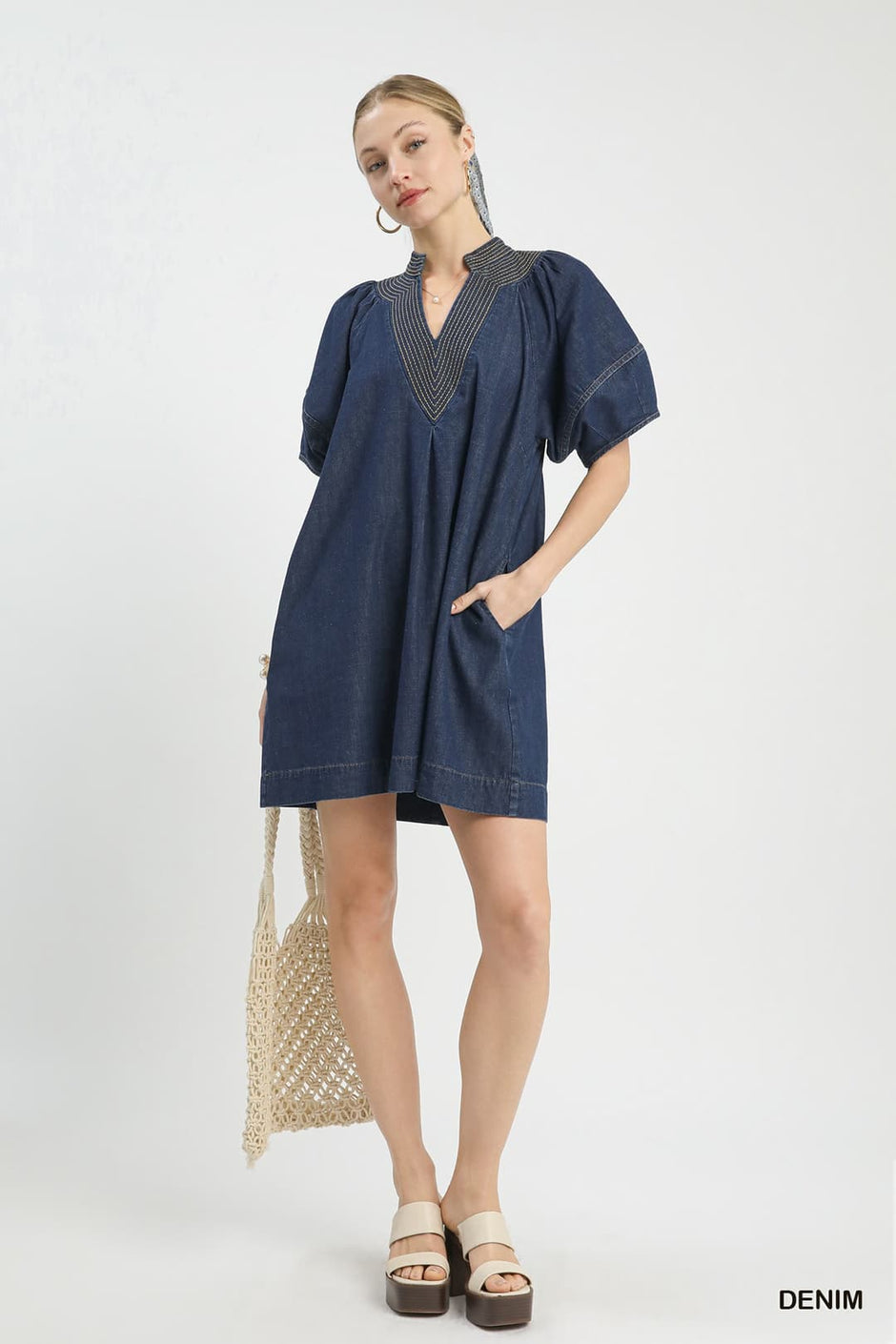 Woman wearing the Marie Washed Denim Mini Dress with a V-neckline and short puff sleeves.