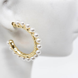 Medium gold tone hoop earrings featuring a white pearl center with light weight pierced silhouette