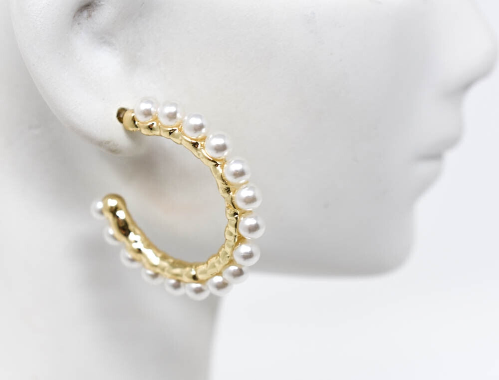 Elegant gold tone hoop earrings with white pearls on a mannequin ear.
