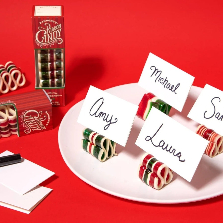 Mini ribbon candy used as place card holders for Amy, Michael, and Laura on a white plate.