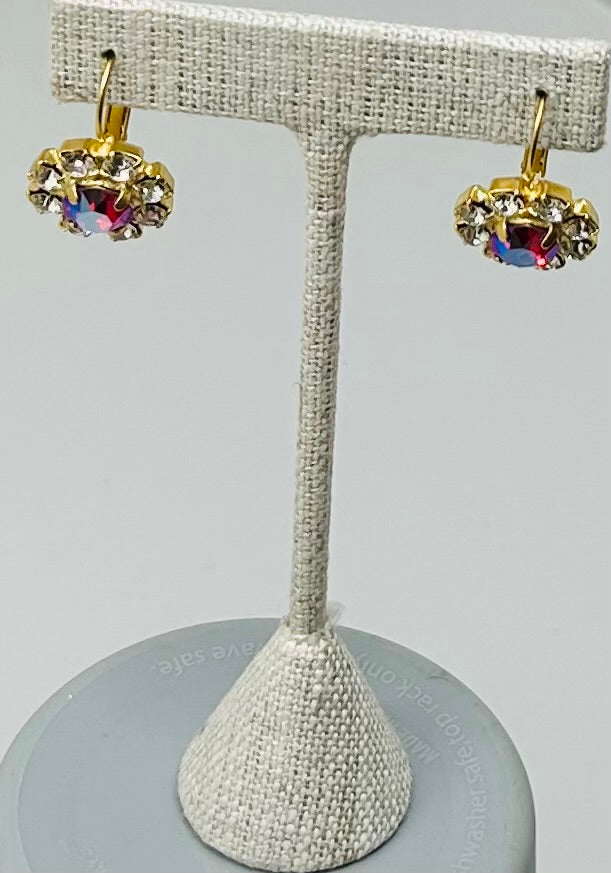 Gold leverback earrings with a round red center stone surrounded by a pave halo of clear crystals.