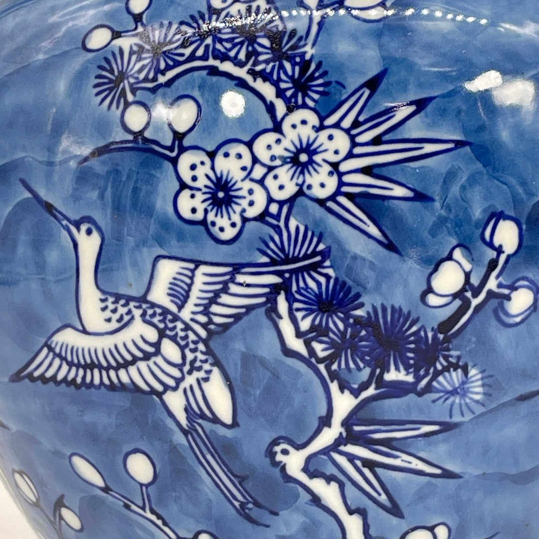 Close-up of blue and white ceramic ginger jar featuring a crane and blossoming tree branches.