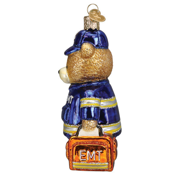 Side view of a glass EMT teddy bear ornament wearing a blue uniform and carrying an orange bag.