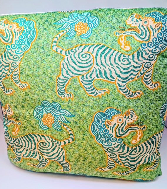 Green pillow with a repeating pattern of stylized tigers and clouds in teal and orange.