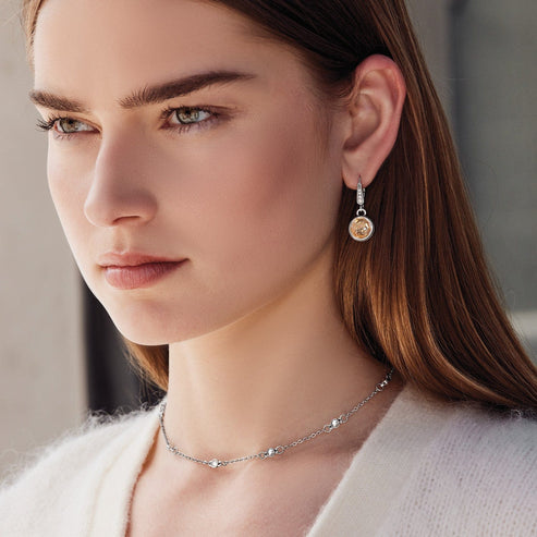 A woman wearing silver-plated Meridian Aurora Leverback Earrings with round amber-colored crystals.