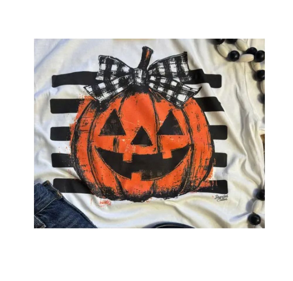 White t-shirt with a jack-o'-lantern graphic, a plaid bow, and black horizontal stripes.