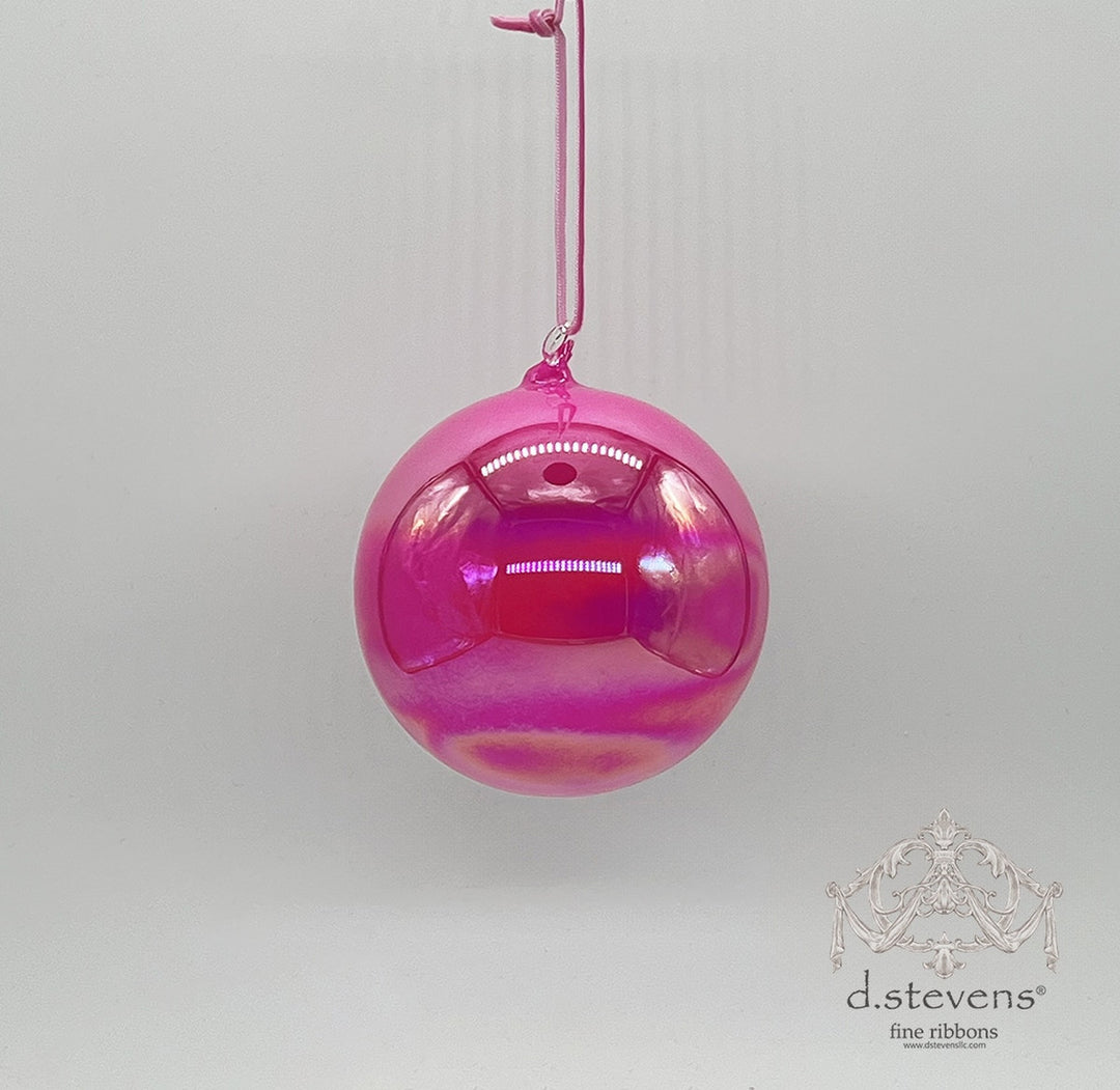 100mm hot pink iridescent hand-blown glass ball ornament hanging from a pink cord.