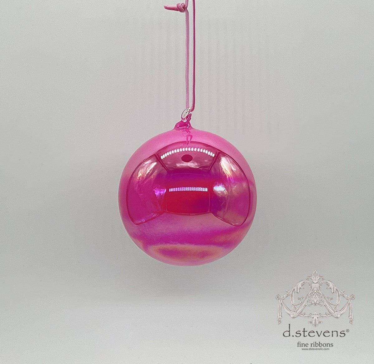 100mm hot pink iridescent hand-blown glass ball ornament hanging from a pink cord.