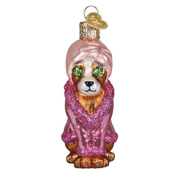 Glass dog ornament wearing a pink robe and turban with green cucumber slices over its eyes.