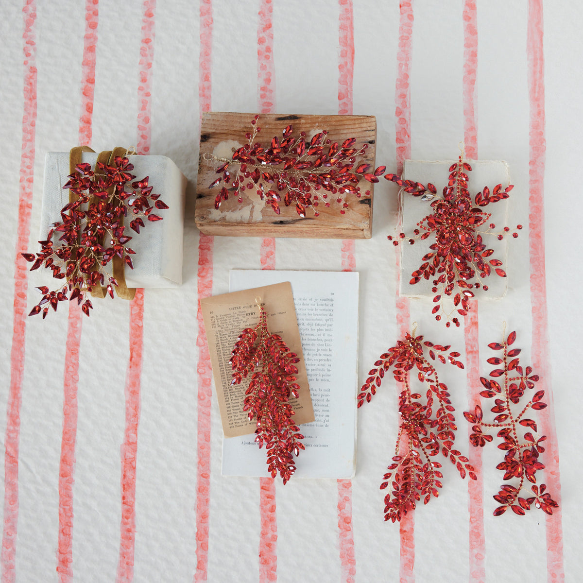 Red acrylic and wire jeweled ornaments in various leaf and spray designs on a striped background.