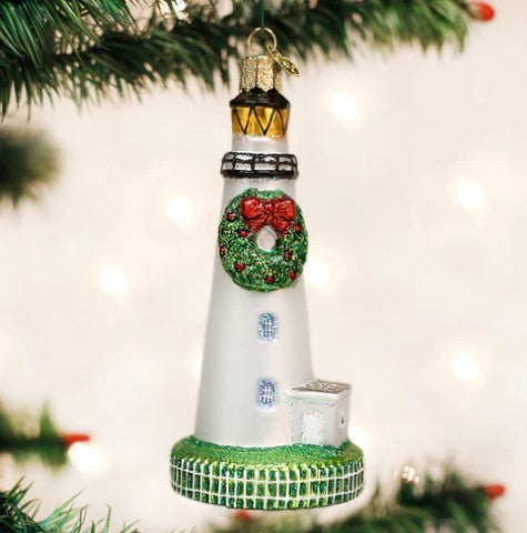 Ocracoke Lighthouse glass ornament with a festive wreath and red bow hanging on a Christmas tree.