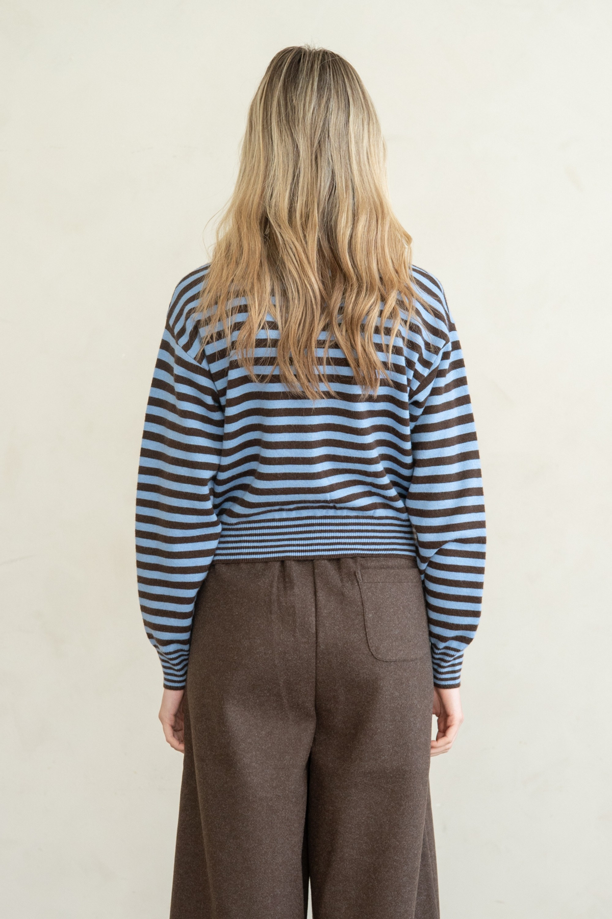 Back view of a woman wearing the Marian blue and brown striped button front cardigan and brown pants