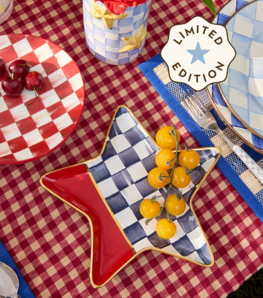 Mackenzie Childs 1776 Ceramic Star Plate with red and blue checkered patterns on a picnic table.