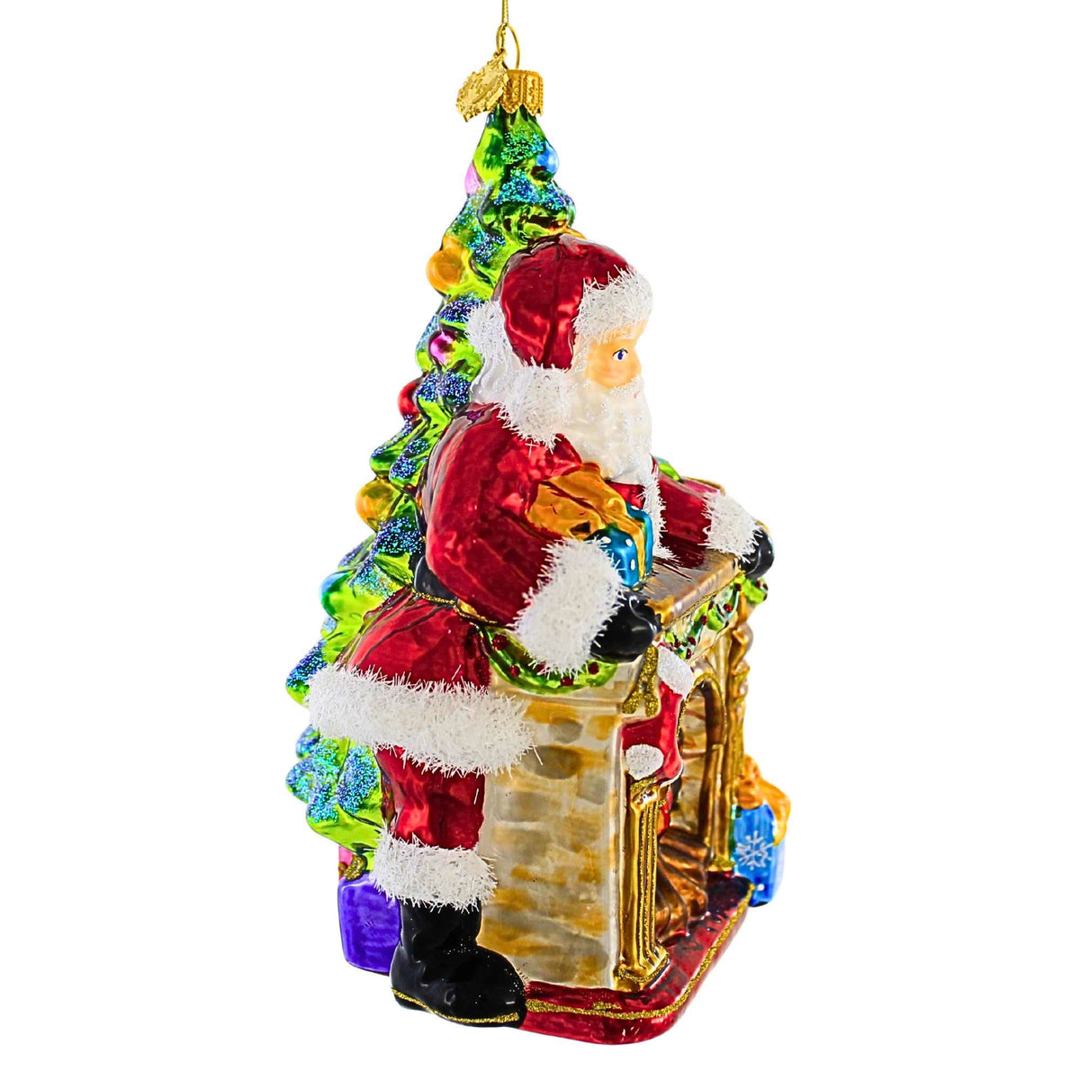 Glass Santa ornament standing by a fireplace next to a decorated Christmas tree.