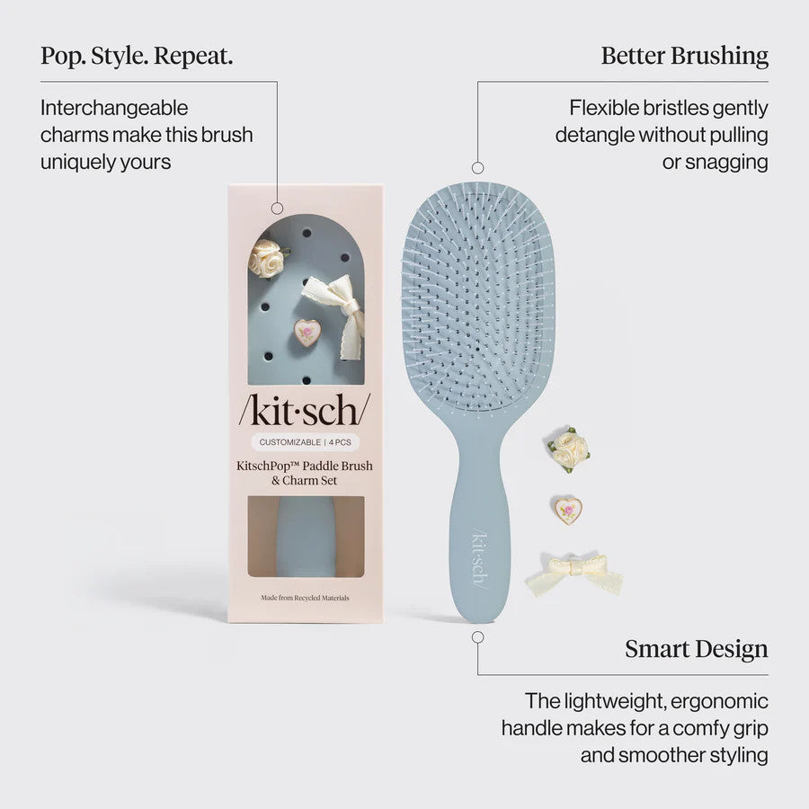 Recycled plastic paddle brush with ergonomic handle and flexible bristles in neutral tone.