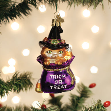 Glass Trick Or Treat Kitty Ornament featuring an orange cat in a witch hat inside a purple bag.
