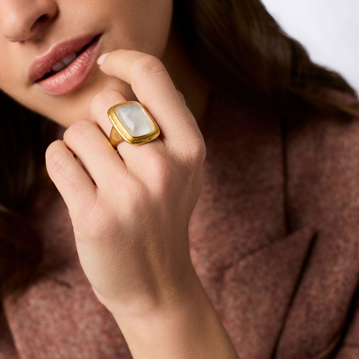 Woman wearing the Sahara Stone Ring, a rectangular white glass stone set in 24K gold plate.